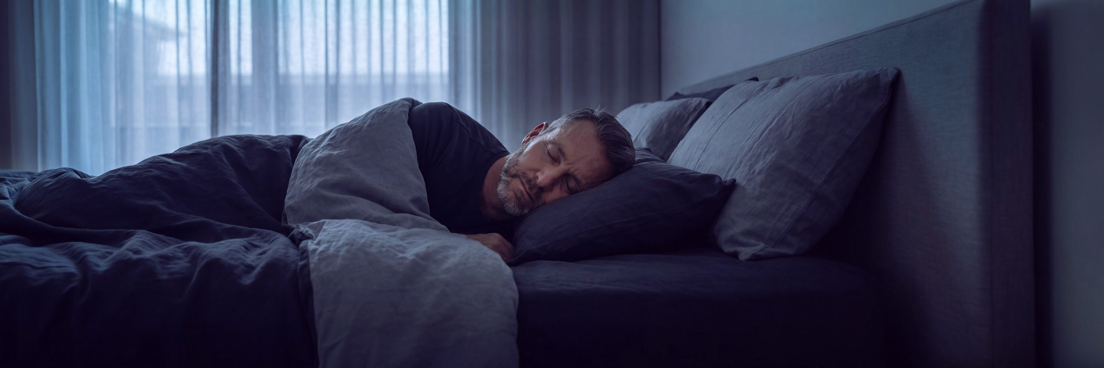 A man asleep in a quiet bedroom in the early morning